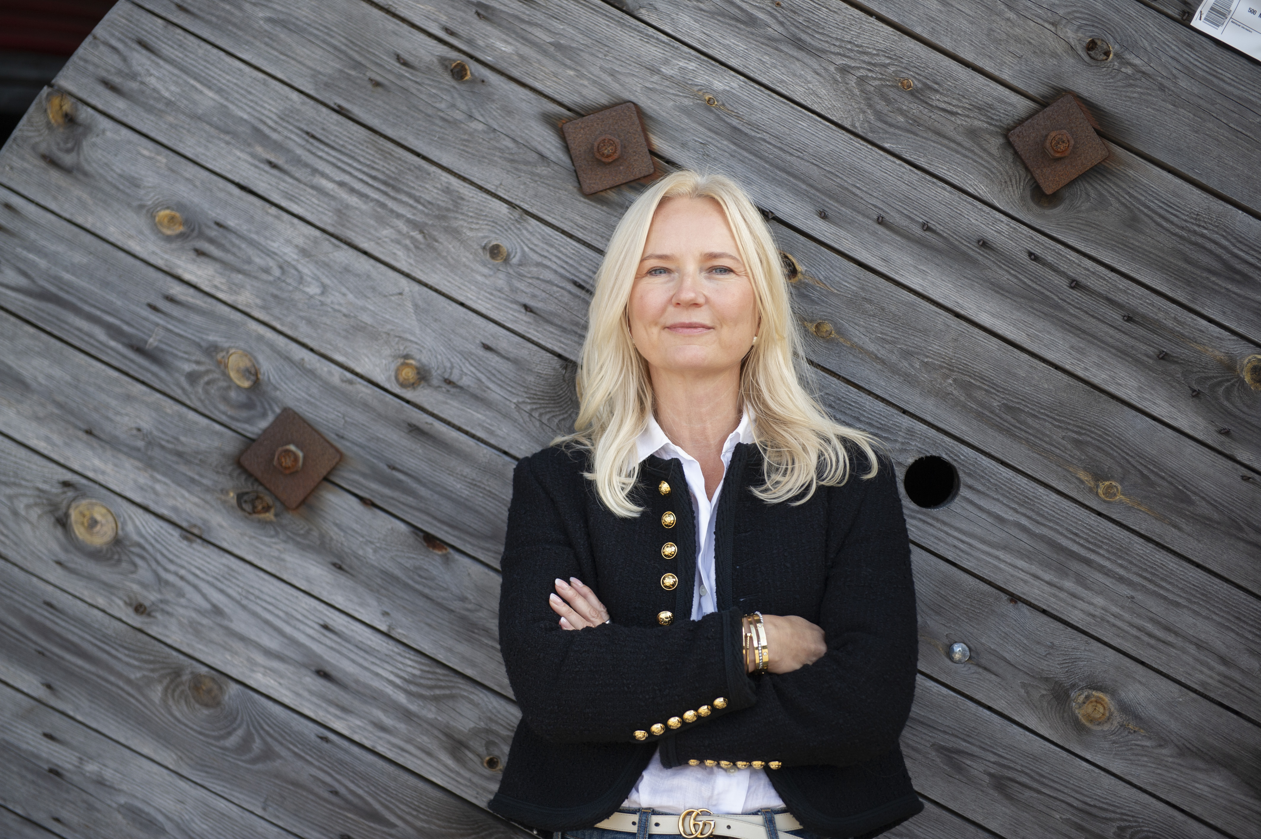 Kvinna står vid en bakgrund av trä 