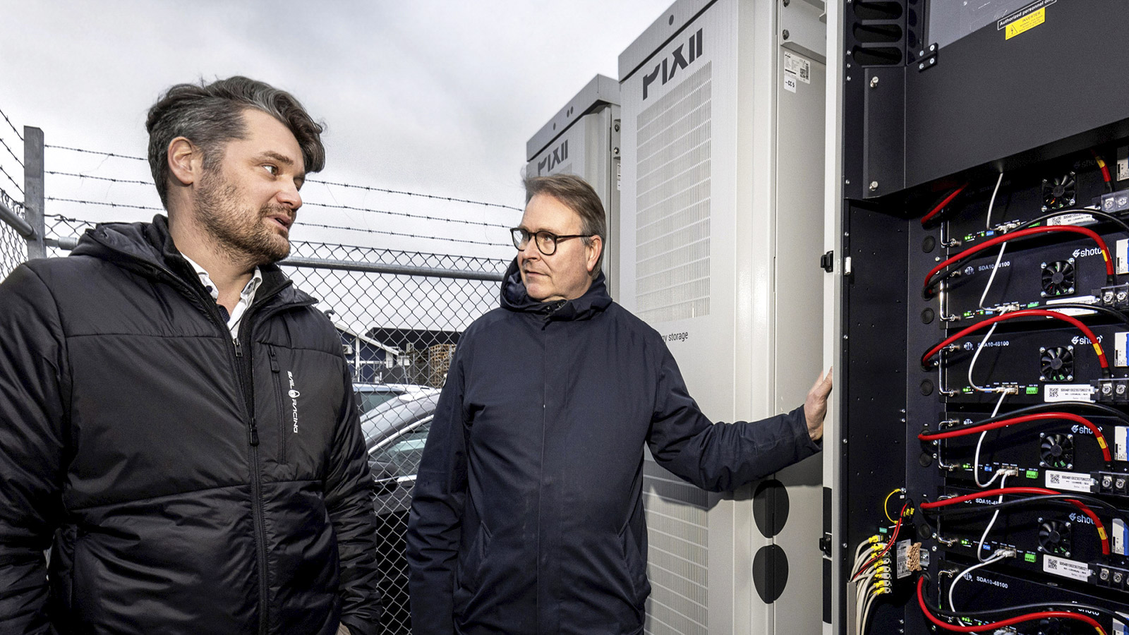 två män står framför ett stort batteri och diskuterar