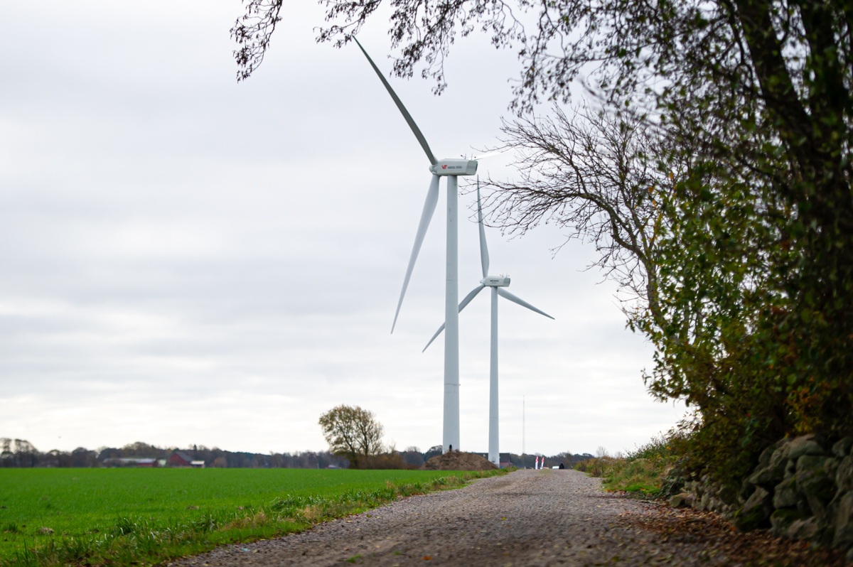 Vindkraftverk på en åker med grönskande träd