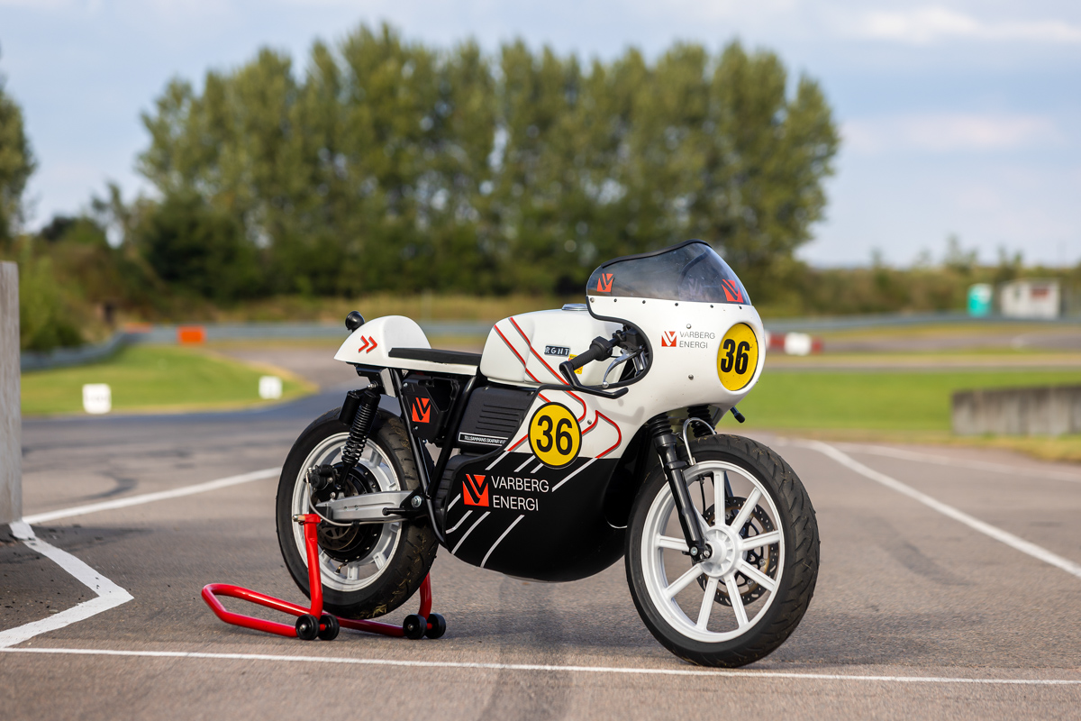 Eldriven vit motorcykel med Varberg Energis logotype  står uppställd med ett rött ställ på en motorbana